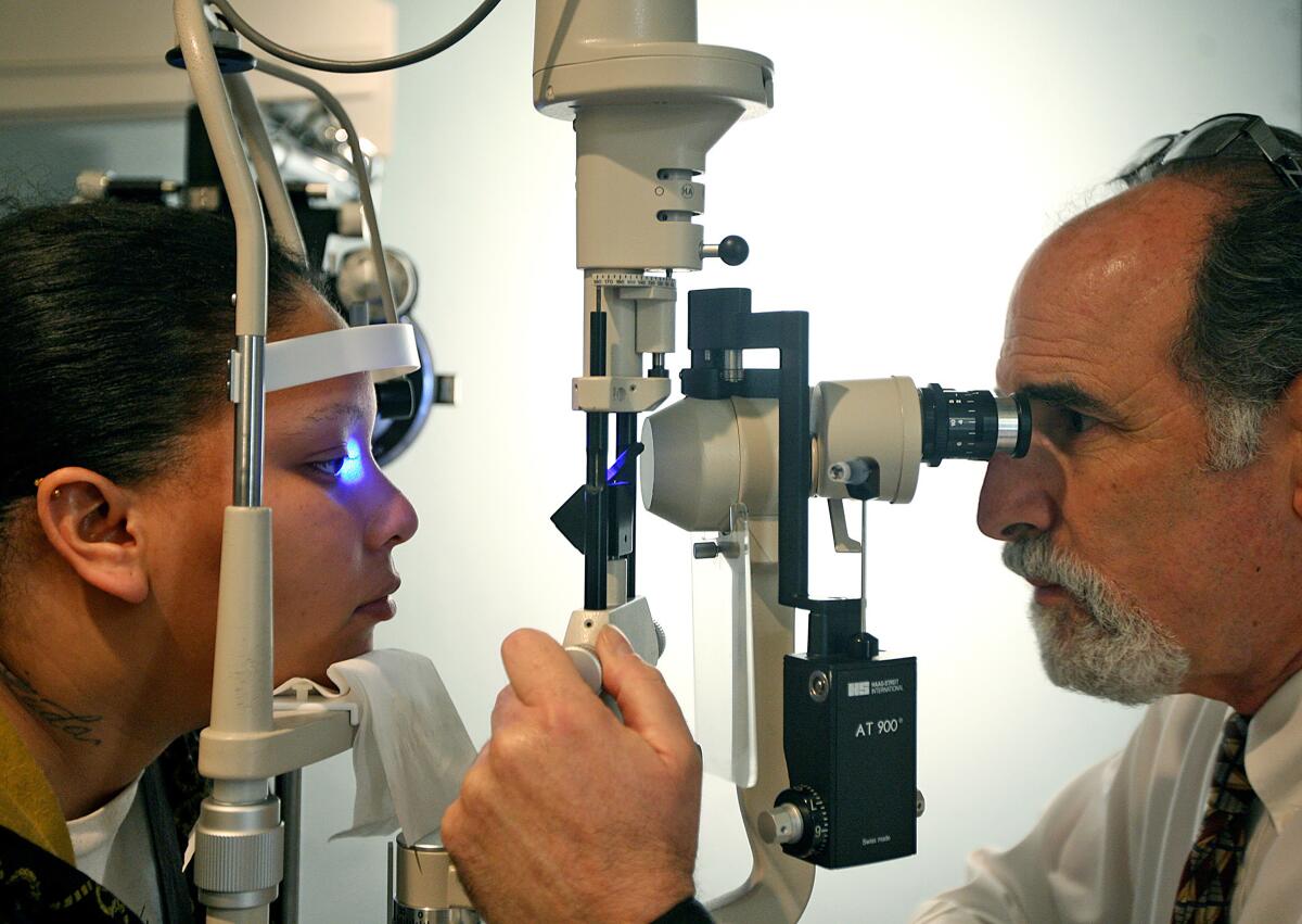 A woman, left, receives an eye exam from an optometrist at his office in Compton in 2010.