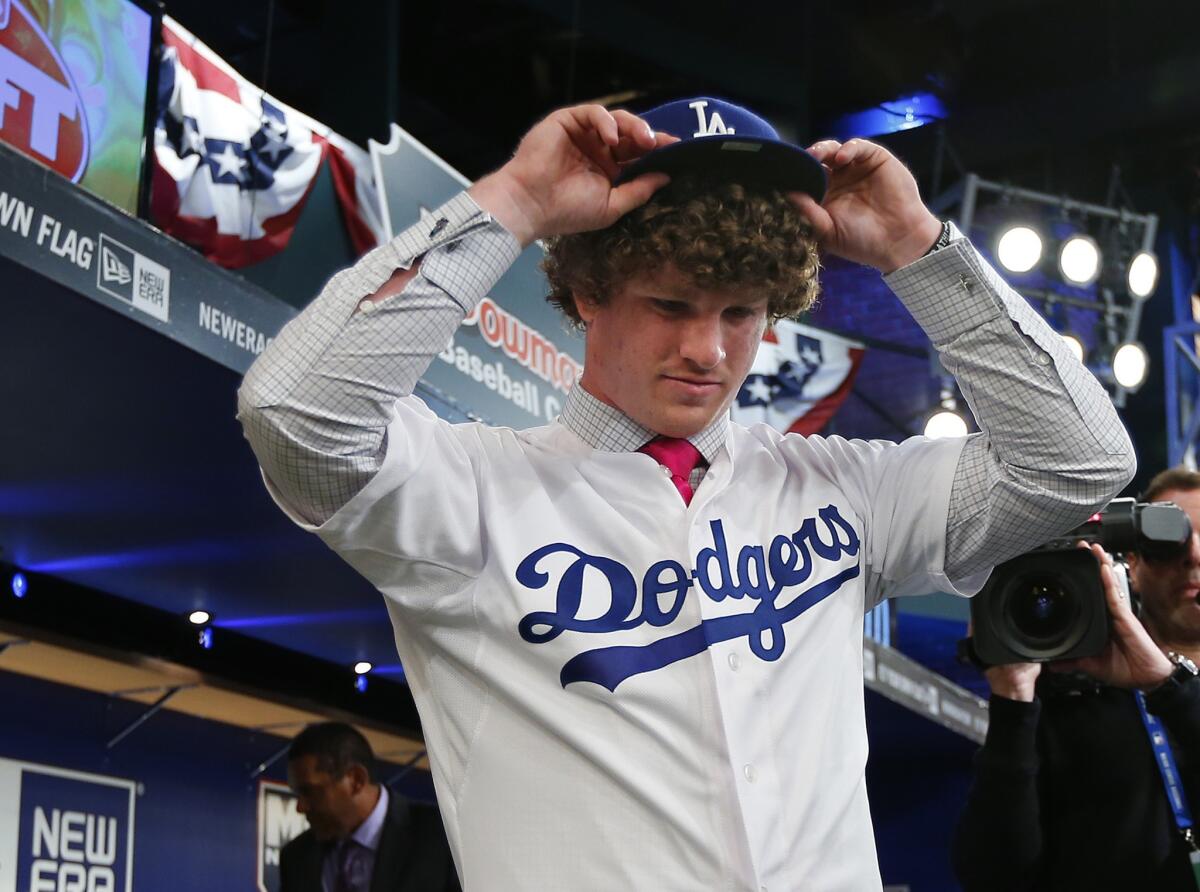 Pitcher Grant Holmes, from South Carolina, puts on a Dodgers hat after being selected in the first round with the 22nd overall pick at the first-year player draft on June 5.