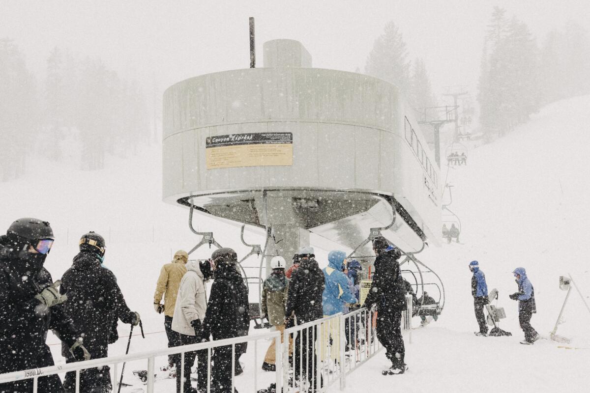 People line up at a chairlift in heavy snow