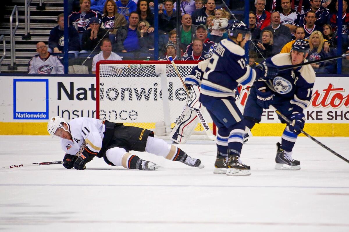 Ducks forward Saku Koivu falls to the ice after being hit by Columbus forward Brandon Dubinsky, far right.