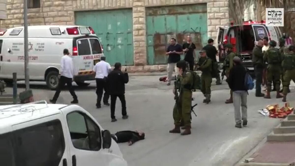 An image grab taken from a video released on March 24, 2016, by B'Tselem, an Israeli non-governmental rights organisation, shows an Israeli soldier aiming his weapon before allegedly shooting in the head and killing a wounded Palestinian assailant.