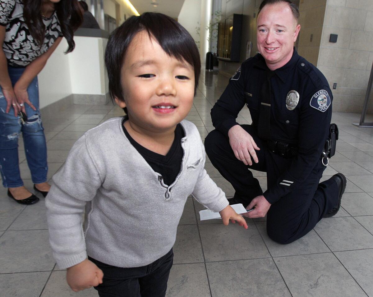 Clayton Cha, 3, runs for the door after giving Glendale police officer James Colvin a hug at the Glendale Police Department on Friday, Jan. 22, 2016. In April, 2015, Colvin was the first on the scene to treat then-2-year-old Clayton, who had fallen on his head from 22 feet onto concrete.