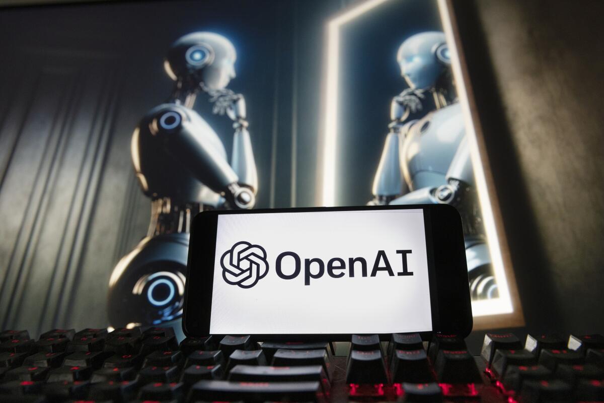 El logotipo de OpenAI se muestra en un teléfono celular con una imagen de computadora 