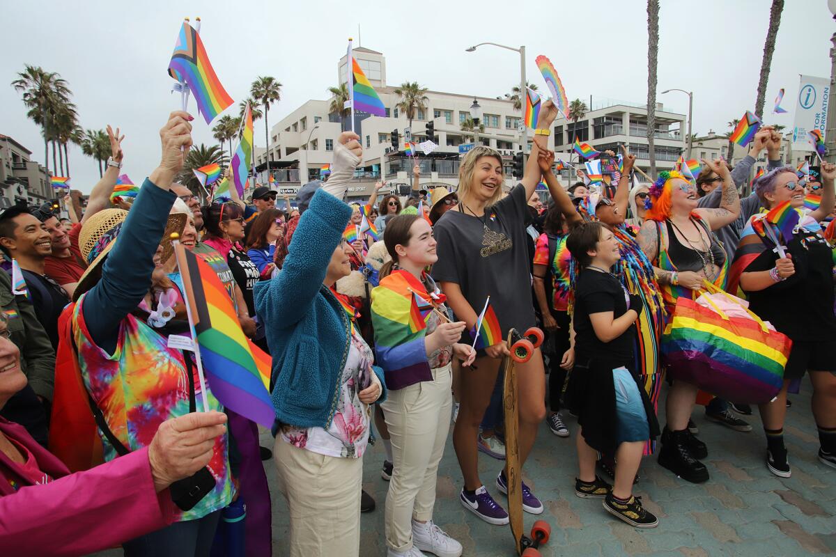 Local activists and LGBTQ+ supporters cheer during a demonstration at the Huntington Beach Pier on Sunday. 