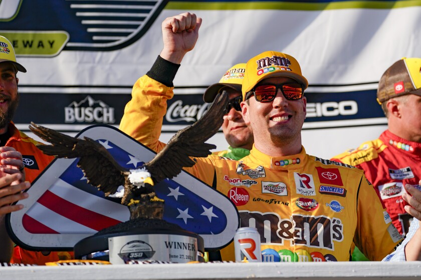 Kyle Busch celebrates with the trophy after winning a NASCAR Cup Series auto race at Pocono Raceway.