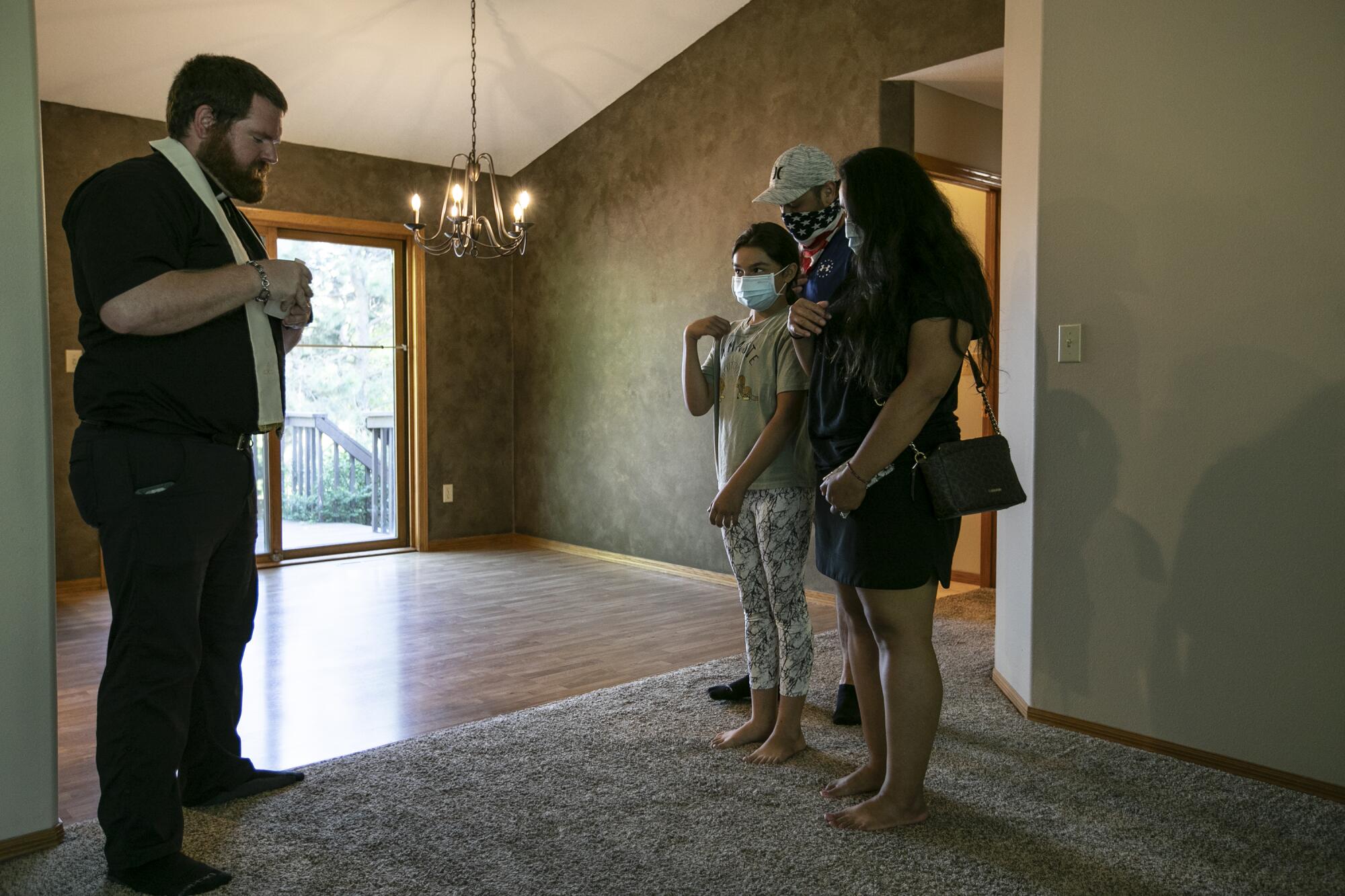 The Rev. Kristopher Cowles prays with the Centeno family, Abby, Abe and Astrid, inside their newly purchased home. 