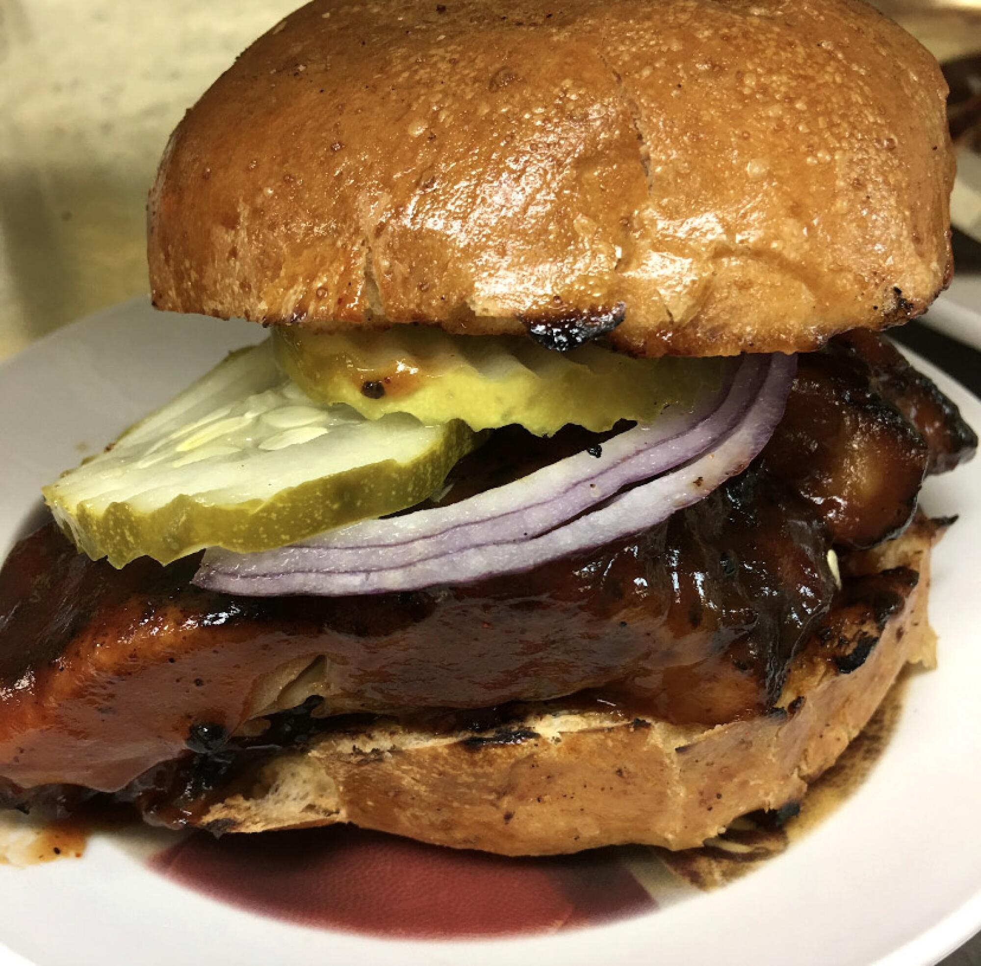 Boneless ribs with sliced onion and pickles on a roll
