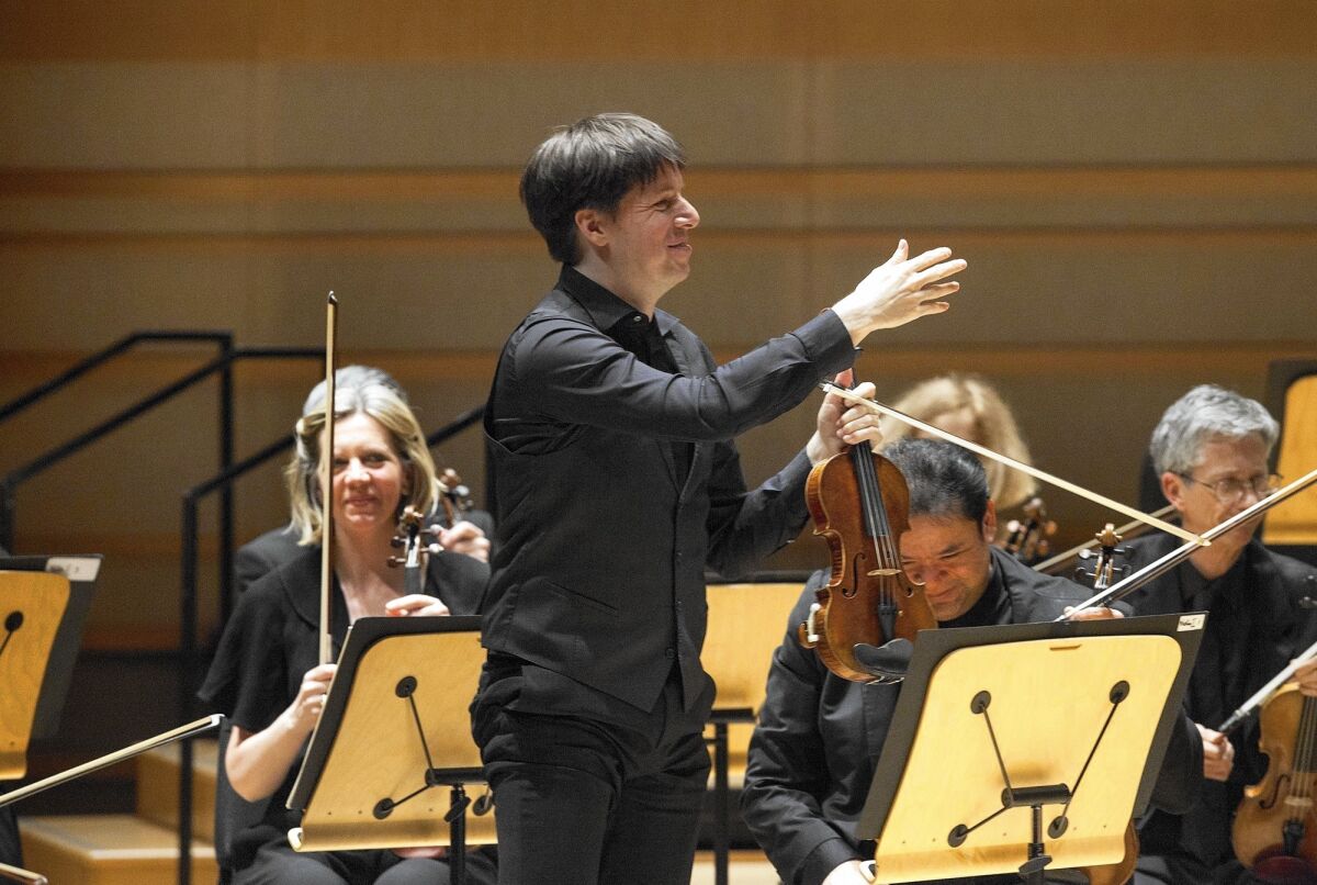 Violinist and conductor Joshua Bell stands to acknowledge members of the Academy of St. Martin in the Fields chamber orchestra after they performed Prokofiev's Symphony No. 1 on Monday in Costa Mesa.