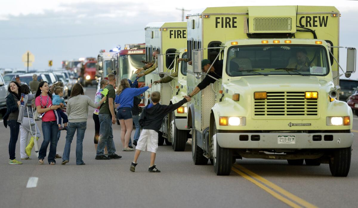 Supporters greet fire crews as they return from their shifts from fighting the Black Forest wildfire outside a fire camp at Pine Creek High School in Colorado Springs, Colo., on Sunday.