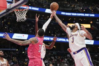 El alero de los Wizards de Washington Kyle Kuzma y el alero de los Lakers de Los Ángeles Anthony Davis estiran el brazo para alcanzar un rebote en el encuentro del domingo 4 de diciembre del 2022. (AP Foto/Jess Rapfogel)