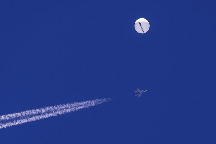 FILE - In this photo provided by Chad Fish, a large balloon drifts above the Atlantic Ocean, just off the coast of South Carolina, with a fighter jet and its contrail seen below it, Saturday, Feb. 4, 2023. A missile fired on Feb. 5 by a U.S. F-22 off the Carolina coast ended the days-long flight of what the Biden administration says was a surveillance operation that took the Chinese balloon near U.S. military sites. (Chad Fish via AP)