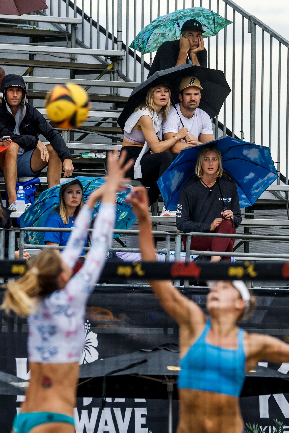 Les fans regardent un match assis sous la pluie avec des parapluies à l'AVP Manhattan Beach Open dimanche.