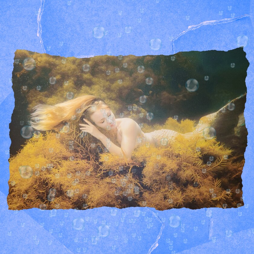 A mermaid sleeping on a bed of moss underwater.