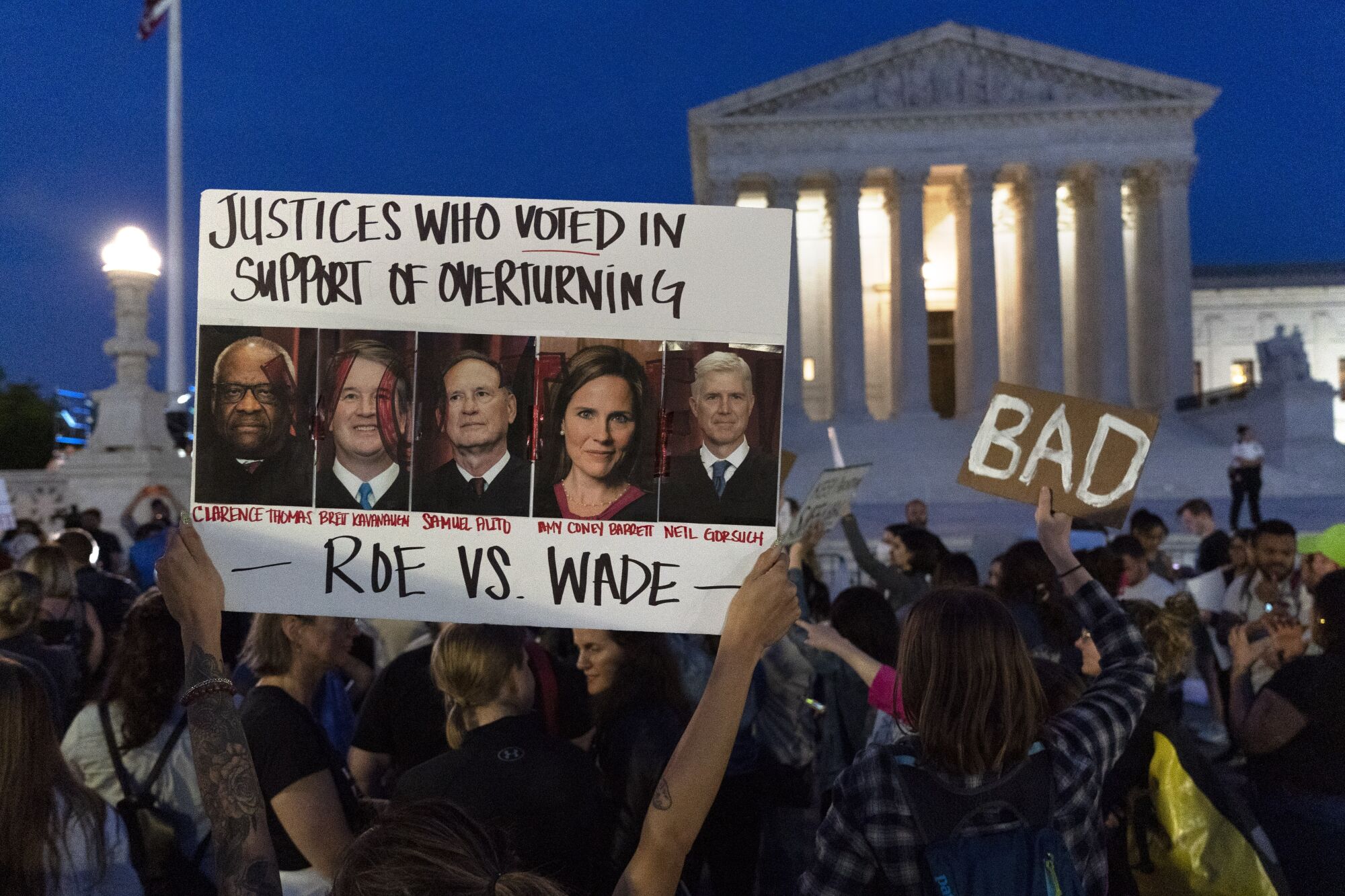 A protester holds up a sign with the pictures of justices who voted to overturn Roe vs. Wade outside the Supreme Court