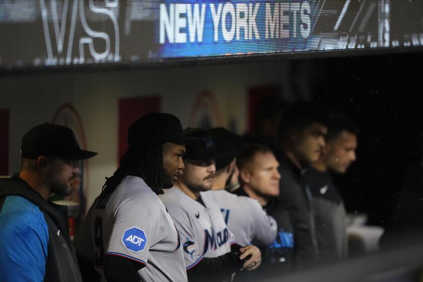 Miami Marlins' Josh Bell, second from left, stands with teammates as they watch the grounds crew members work on the field during a rain delay against the New York Mets early Friday, Sept. 29, 2023, in New York. (AP Photo/Frank Franklin II)