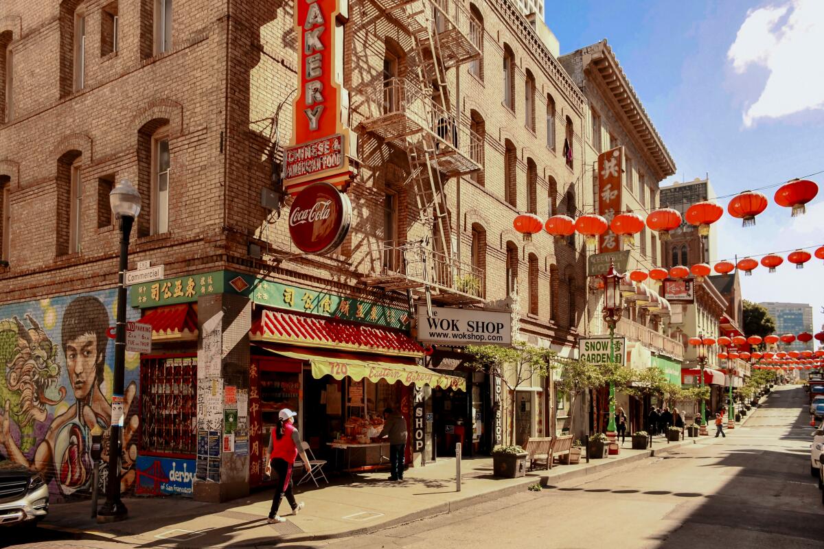 Buildings in Chinatown with a Bruce Lee mural, and red paper lanterns strung across the street.