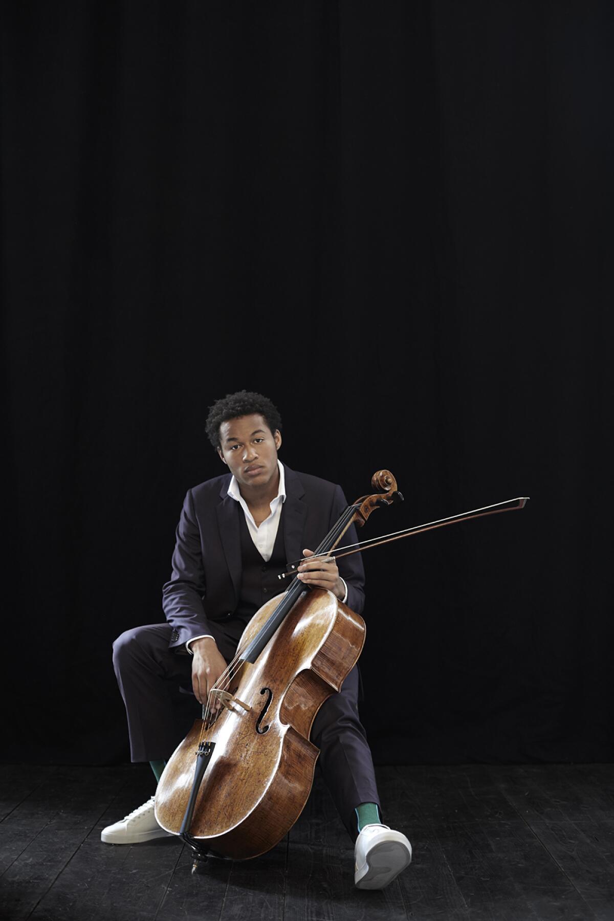 A seated man poses with a cello.