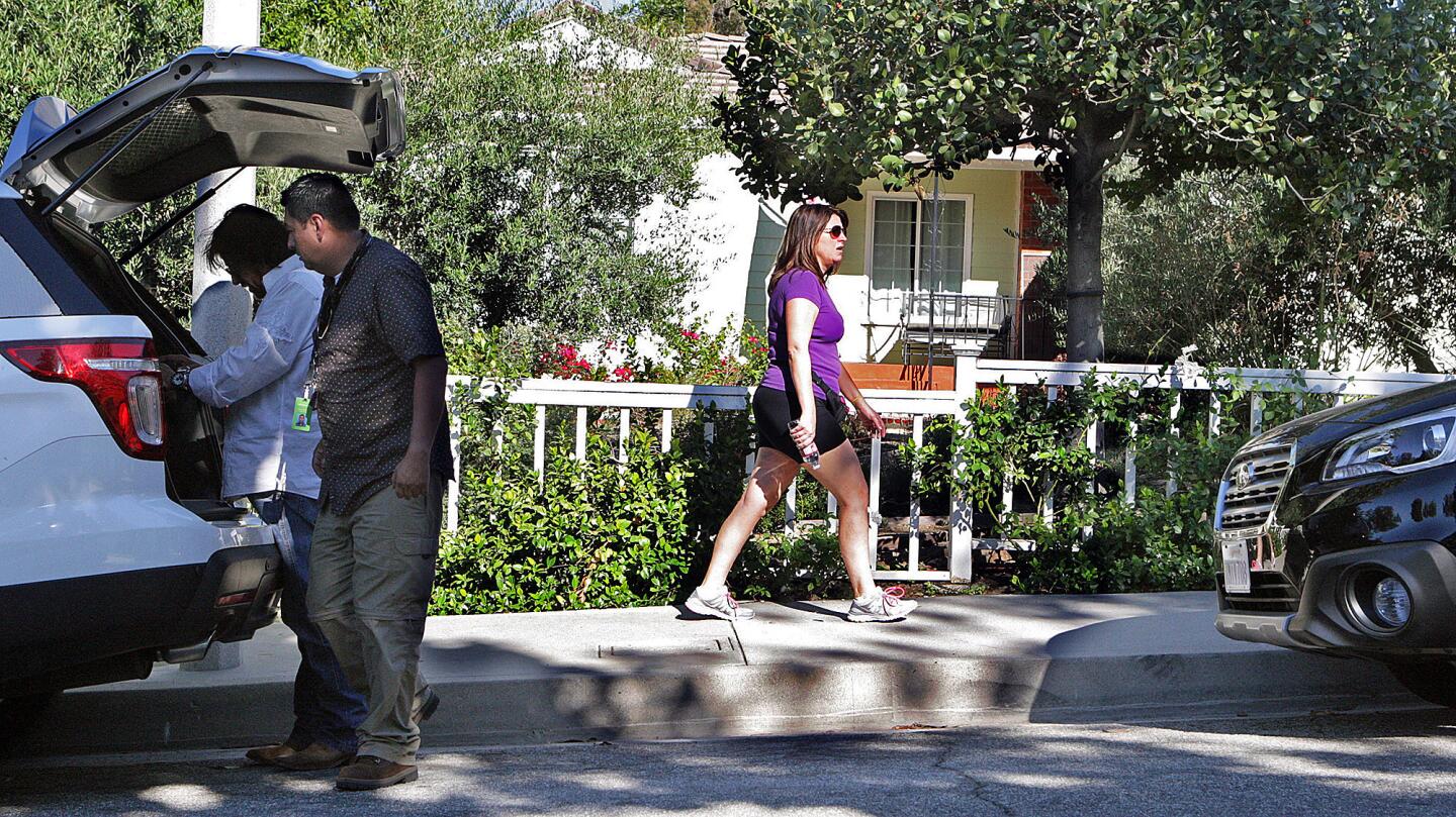 Neighbors out for a walk as news teams prepare for coverage at the scene of a murder-suicide on the 5000 block of Crown Avenue in La Cañada Flintridge on Monday, Sept. 7, 2015. On Sunday night, a 5-year veteran of the Los Angeles County Fire Department shot and killed his wife, a 2-year veteran of the Sheriff's Department. He then killed himself at a county Fire Department facility in Pacoima, according to officials.