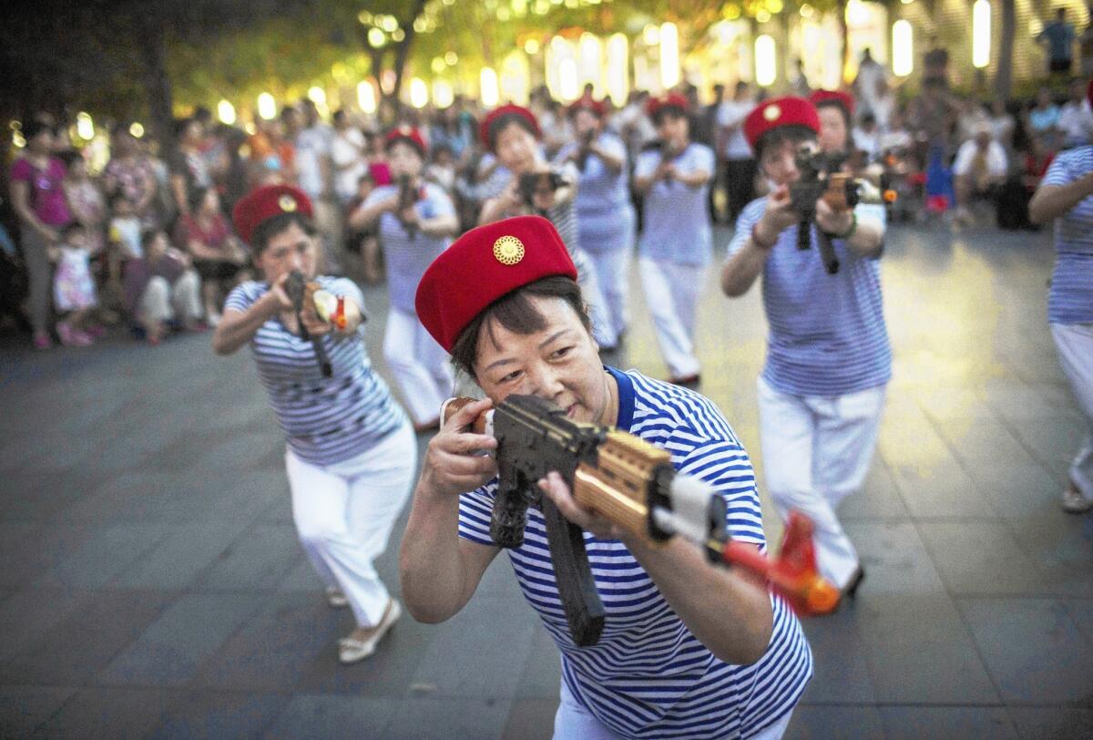 Members of a Chinese dance troupe, armed with prop weapons, reenact wartime scenes during a July 2014 performance of "red songs" at a mall in Beijing.