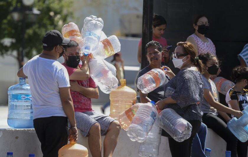 Vecinos esperan para llenar garrafas de plástico con agua en un punto de suministro público en Monterrey
