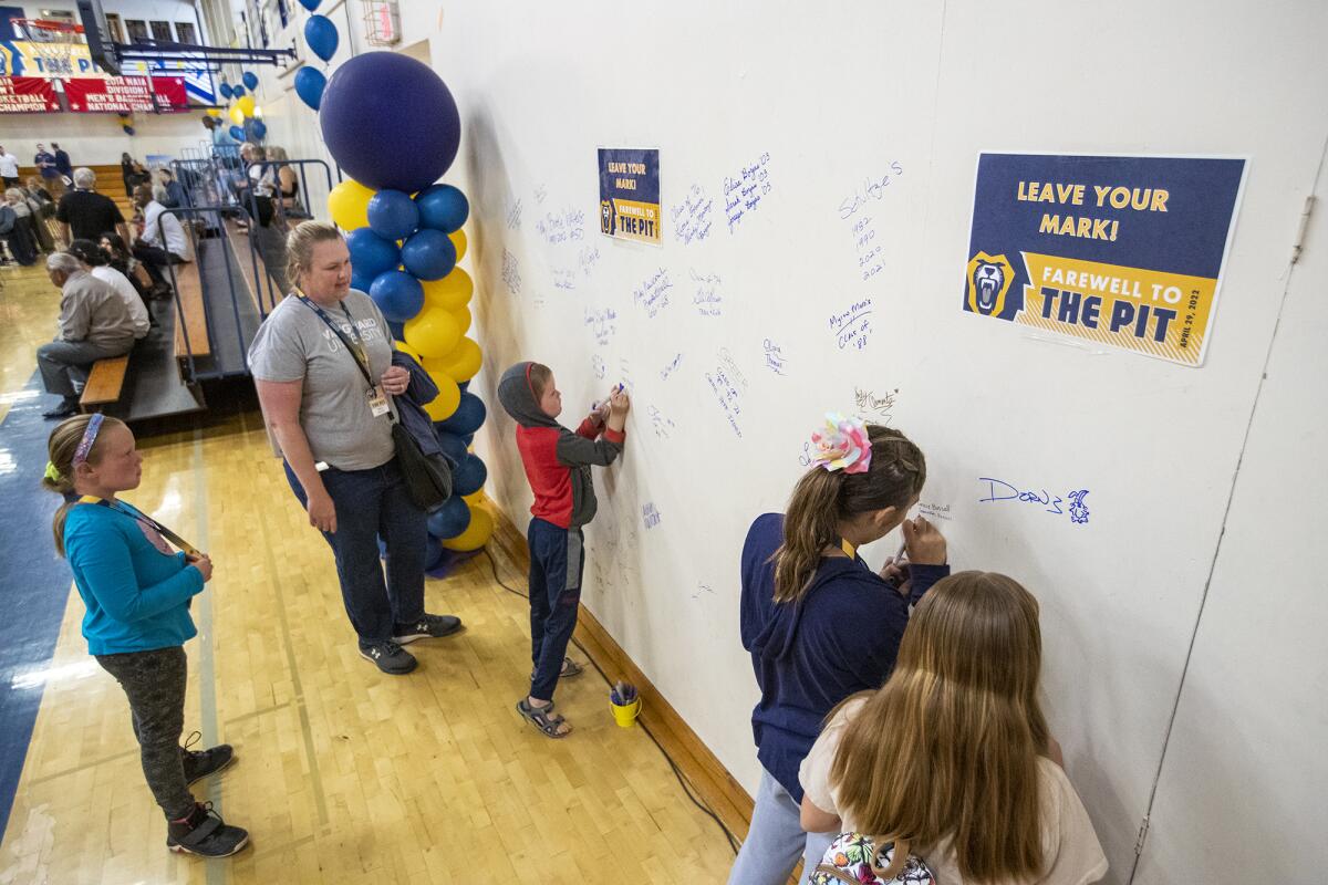 Kelly Walters, center, watches her son, Kaden, signs a wall during a ceremony at Vanguard.