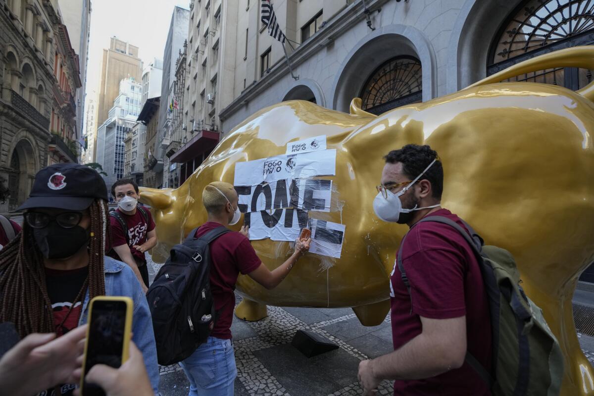 Activists paste the Portuguese word "hungry" on a bull sculpture 