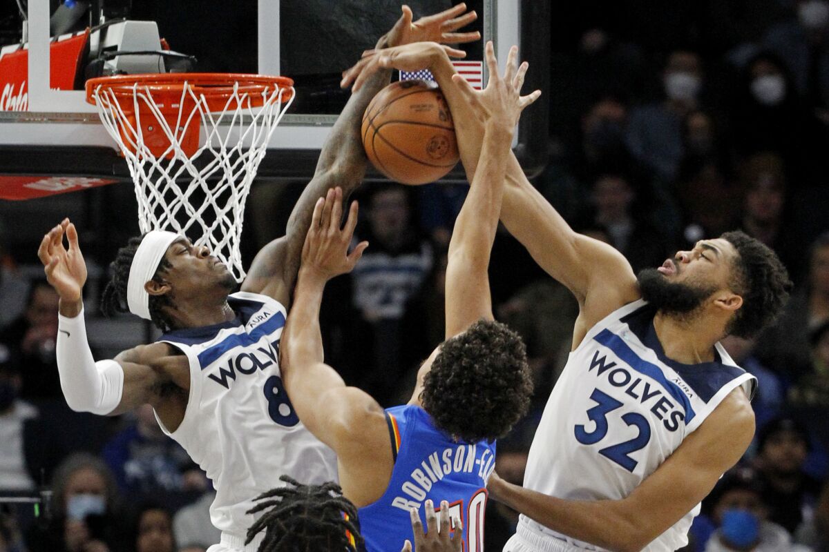 Oklahoma City Thunder center Jeremiah Robinson-Earl (50) tries to go to the basket as Minnesota Timberwolves forward Jarred Vanderbilt (8) and center Karl-Anthony Towns (32) defend him in the first quarter of an NBA basketball game Wednesday, Jan. 5, 2022, in Minneapolis. (AP Photo/Bruce Kluckhohn)