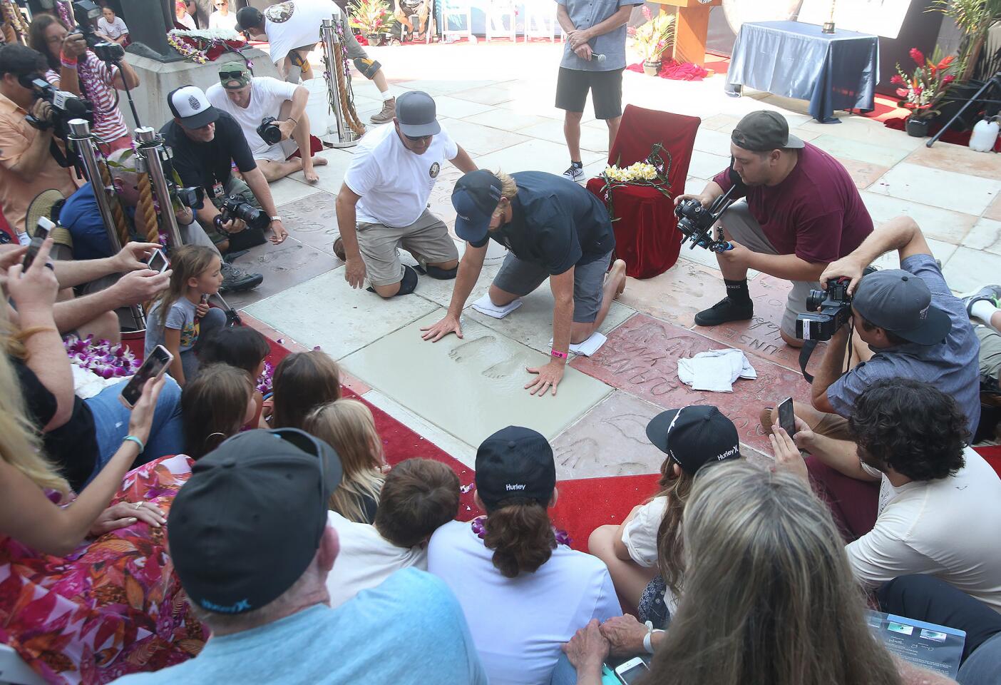 Huntington Beach's Brett Simpson plants his hands into cement as he is inducted into the Surfers' Hall of Fame in front of Huntington Surf and Sport on Friday.