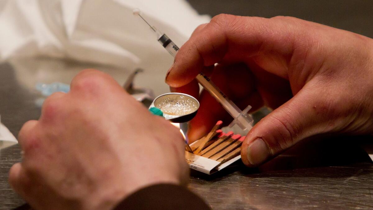 A man prepares heroin he bought on the street to be injected at the Insite safe injection clinic in Vancouver.