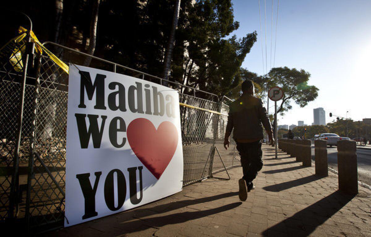 A man walks past a placard left in support of former South African President Nelson Mandela outside the Mediclinic Heart Hospital in Pretoria. Mandela's clan name is Madiba.