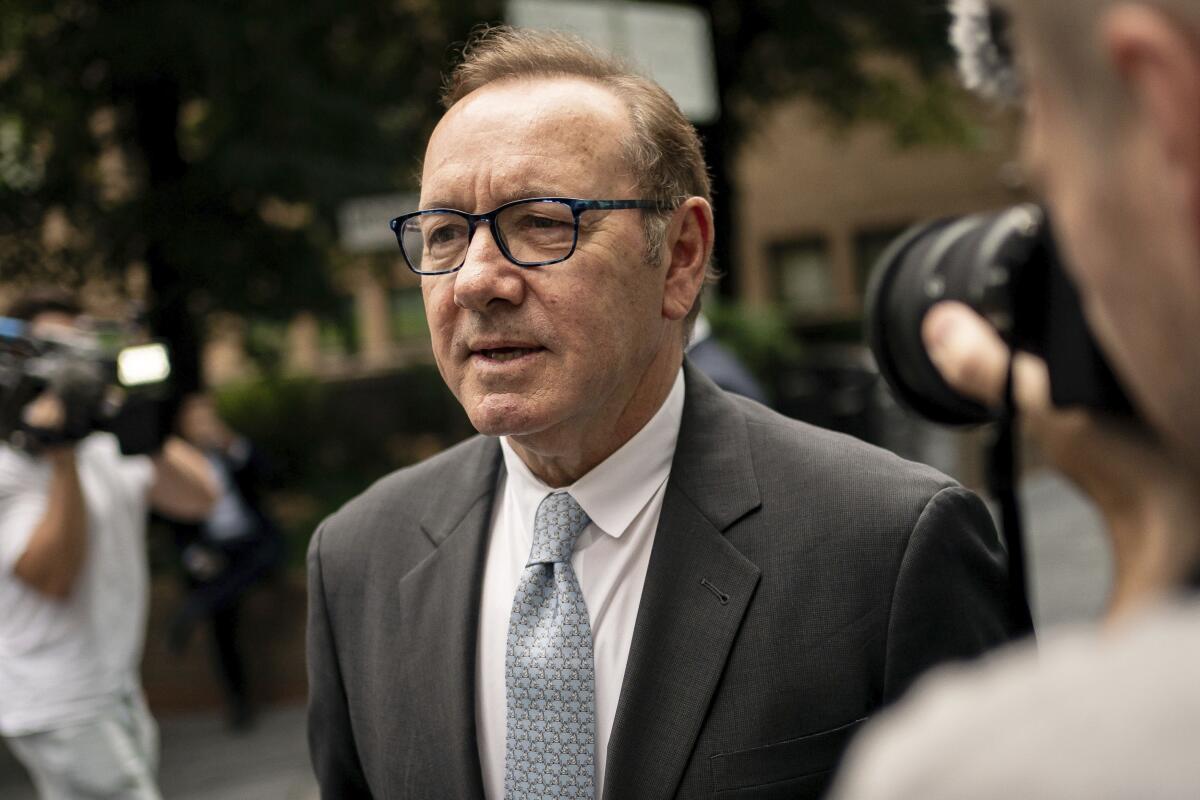 Kevin Spacey is photographed in a gray suit and black-framed glasses as he walks into a courthouse.