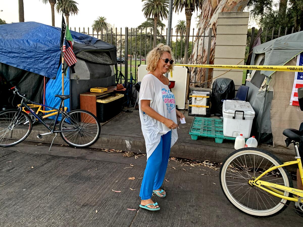A person stands in the street next to tents on the sidewalk.