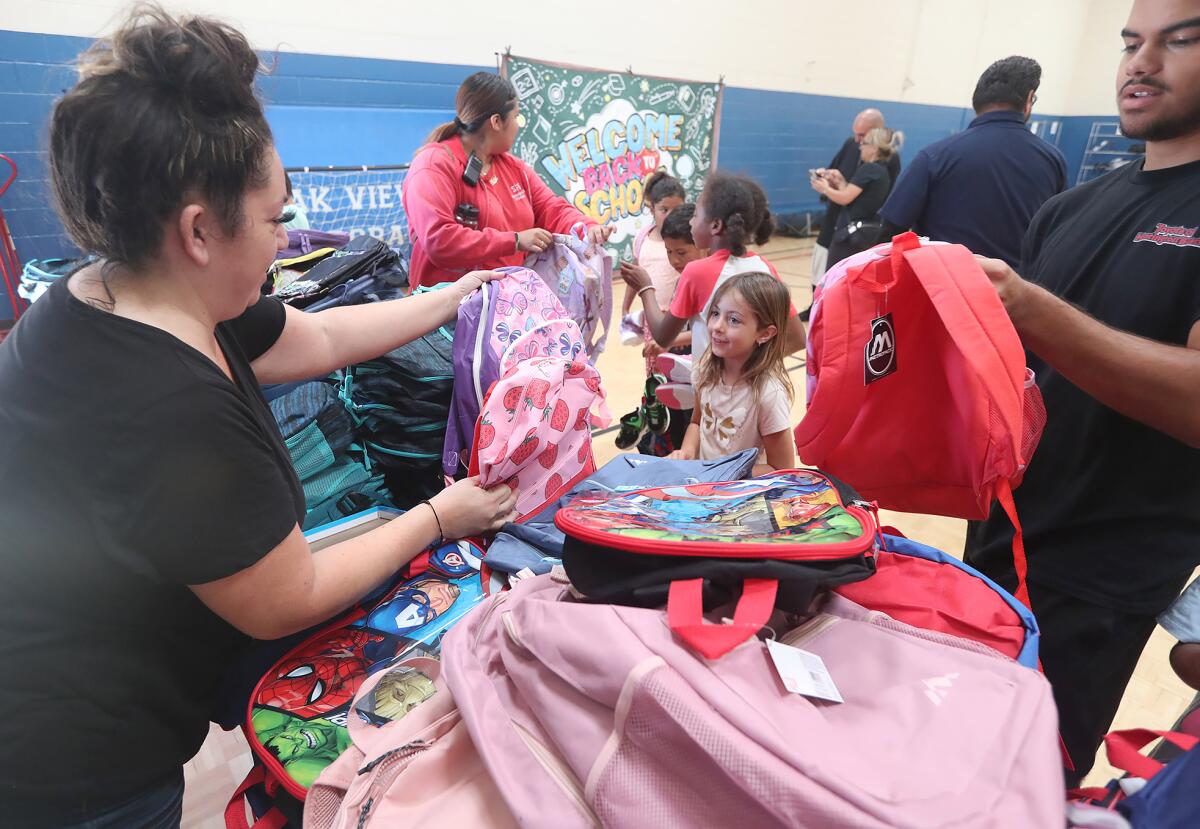 Volunteers including Ray Ordaz, right, hand out backpacks during Monday's giveaway.