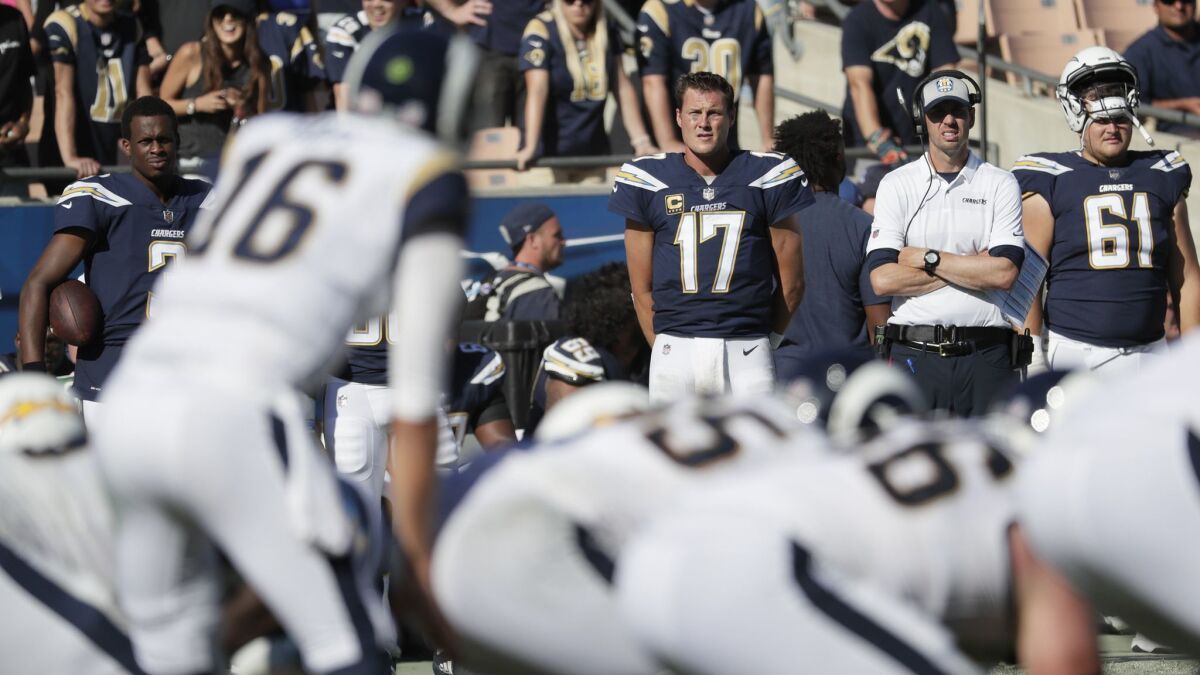 Chargers quarterbacks Geno Smith, left, and Philip Rivers watch Rams quarterback Jared Goff lead the team at the Coliseum.