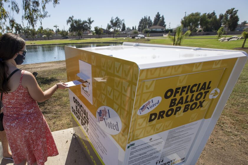 SANTA ANA, CA - OCTOBER 13: Caitlin Harjes, of Orange, places her ballot inside an official Orange County Registrar of Voters ballot Drop Box for the 2020 Presidential General Election at Carl Thornton Park in Santa Ana on Tuesday, Oct. 13, 2020. (Allen J. Schaben / Los Angeles Times)