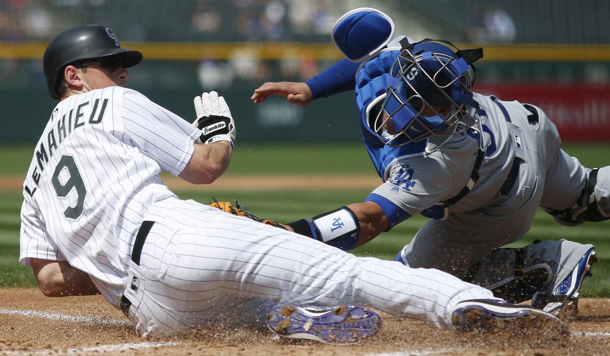 The Colorado Rockies' DJ LeMahieu avoids the tag by Dodgers catcher Carlos Ruiz to score on a double by Nolan Arenado in the first inning of the first game of a doubleheader.