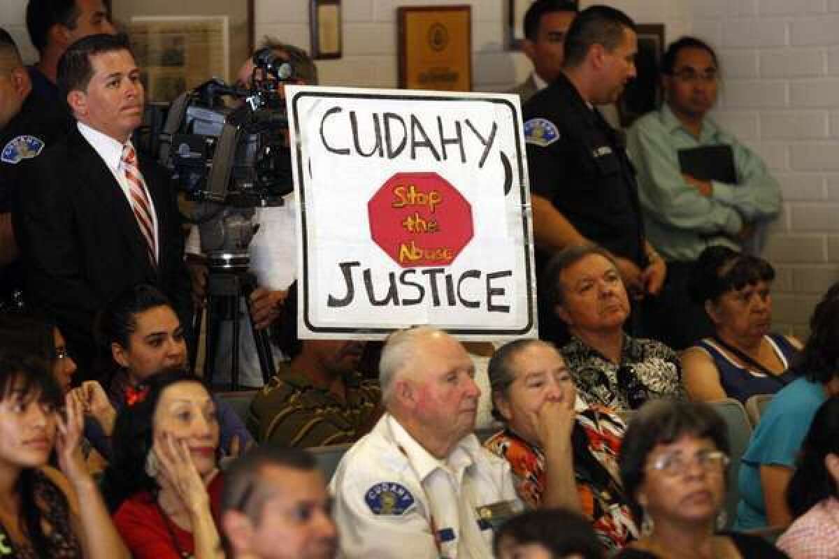 In July, a community activist holds a sign while listening to City Council members with other residents as they rally at City Hall to discuss the restoration of good governance to Cudahy.