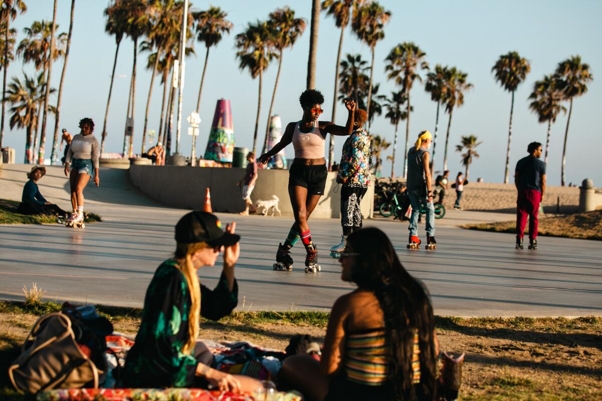 A beachfront skate park draws a crowd of roller skaters.