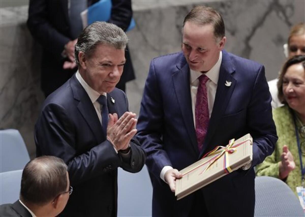 El presidente de Colombia Juan Manuel Santos (izq) agradece los aplausos de los integrantes del Consejo de Seguridad de la ONU tras entregarle al presidente de ese cuerpo Jon Ker una copia de los acuerdos de paz entre su gobierno y las FARC el 21 de septiembre del 2016.