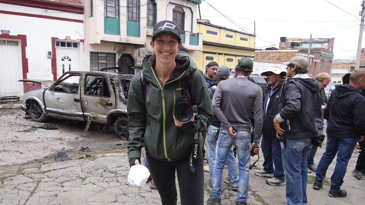 Jennifer Rose Clasen holds a camera and smiles during a shoot.