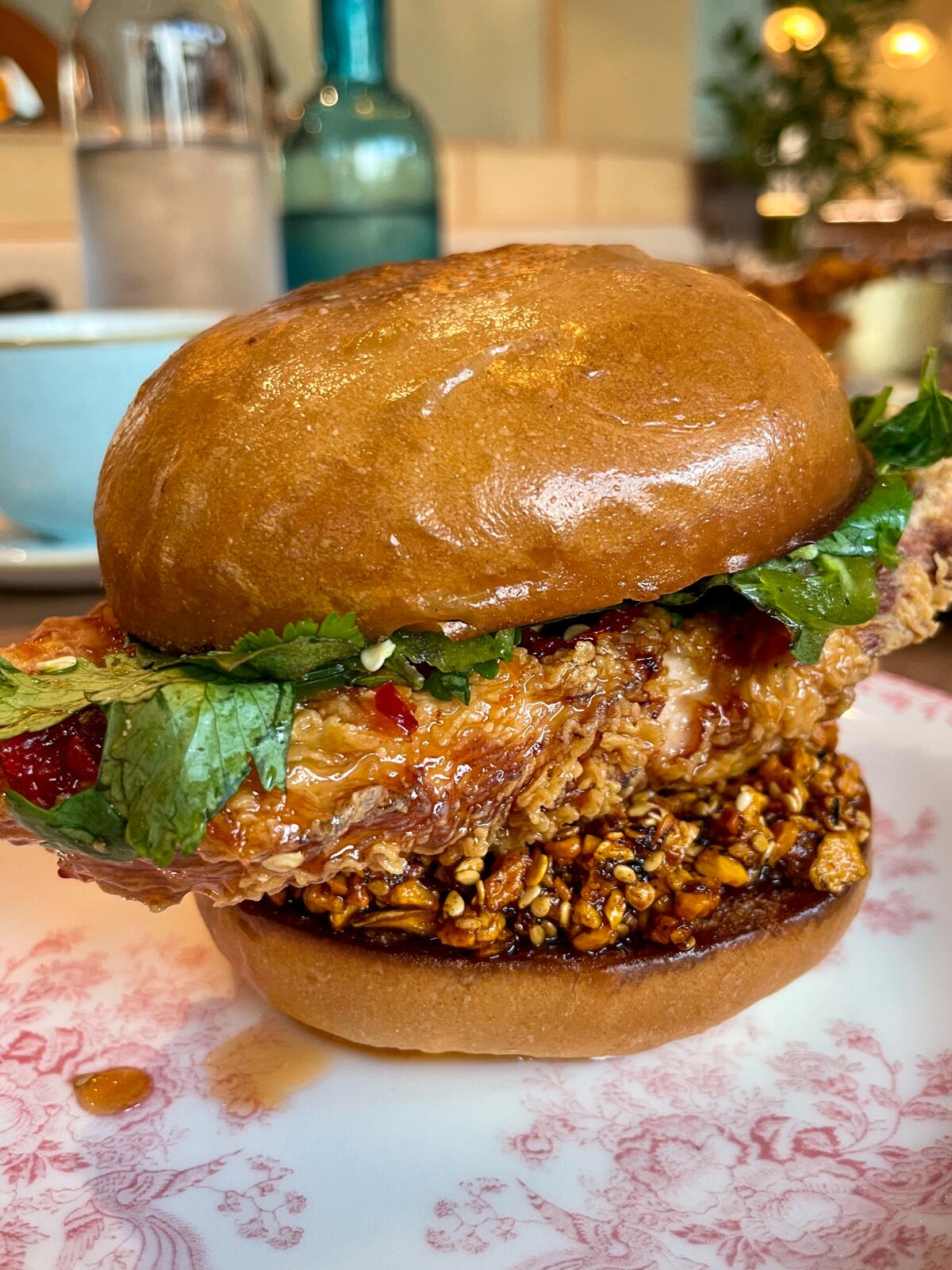 A large piece of fried chicken sticks out from a round bun