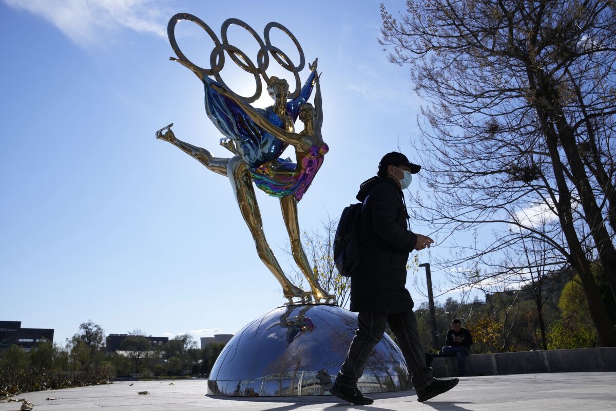 A person walks by a sculpture of ice skaters
