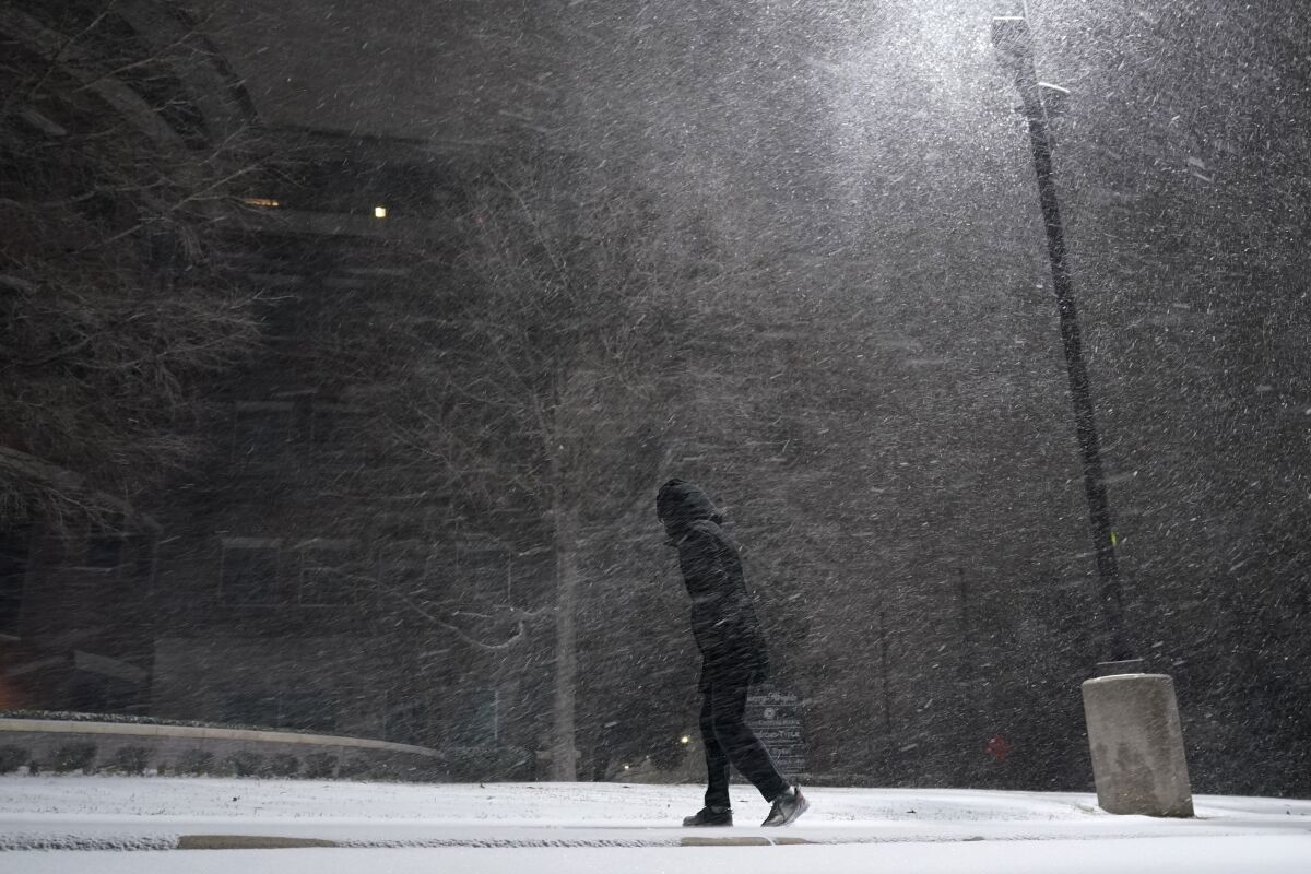 A woman walks through falling snow 
