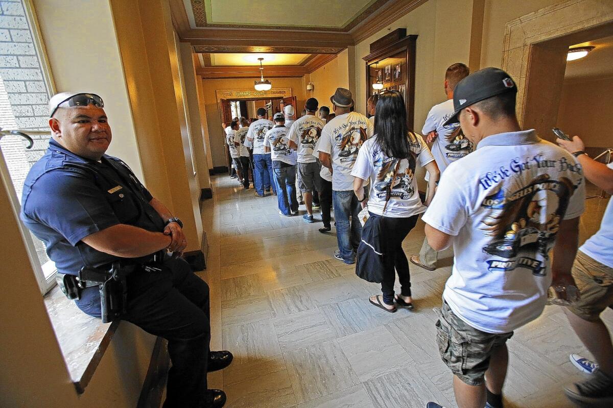 Los Angeles police Officer Luis Ortega, left, watches as other officers head to the City Council chambers. Mayor Eric Garcetti and council members have been trying to hold the line on raises across the city workforce.