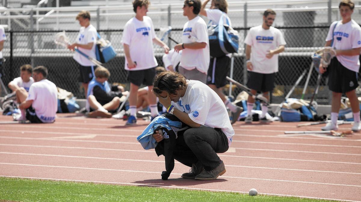 A Corona del Mar High player covers his face after the Sea Kings lost, 10-6, to Loyola in the U.S. Lacrosse Southern Section title game at Valencia High in Placentia on Saturday.