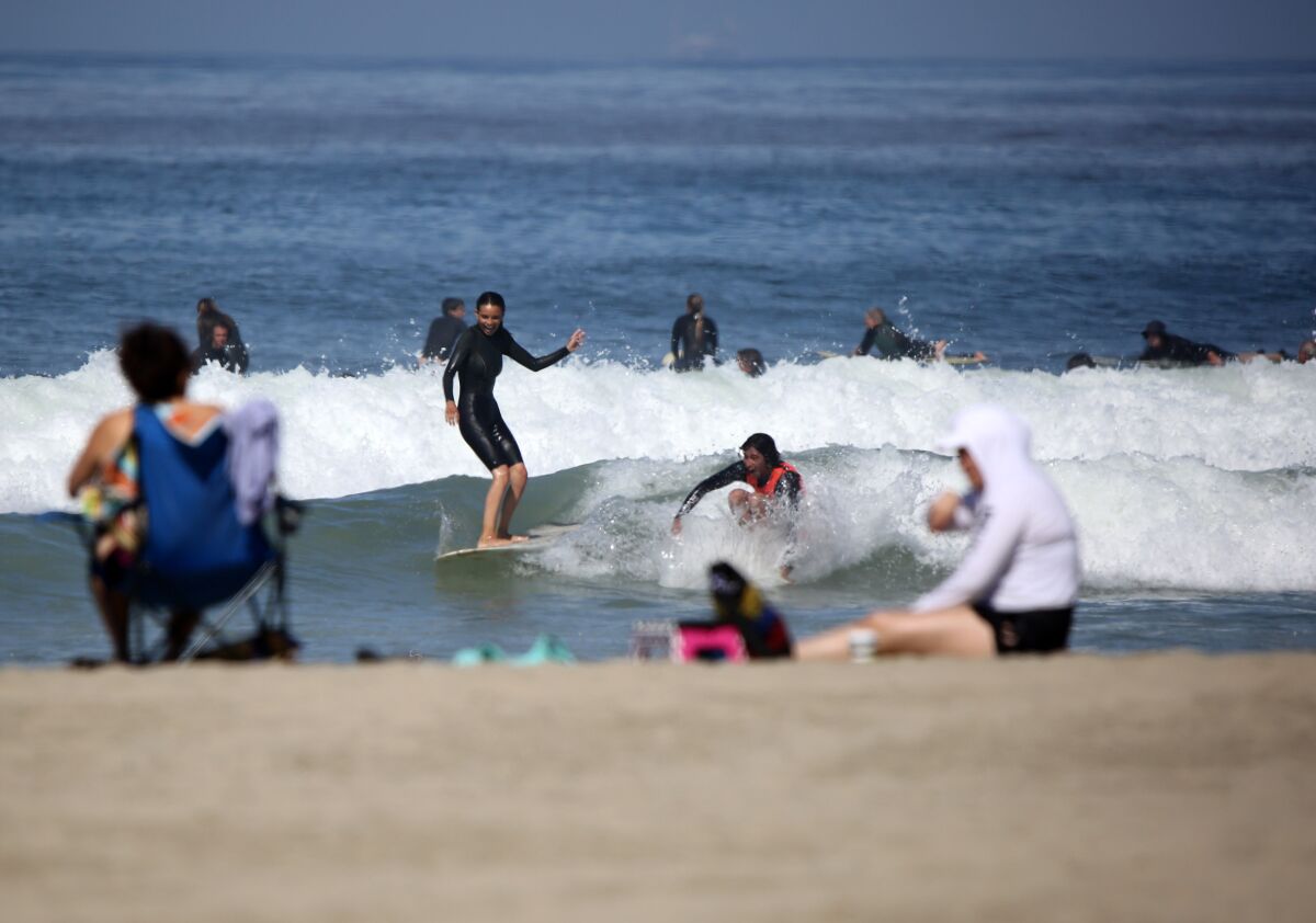One day after Newport Beach opened up its beaches to recreational activities, dozens of surfers took to the water at the Newport Pier in Newport Beach on May 7.