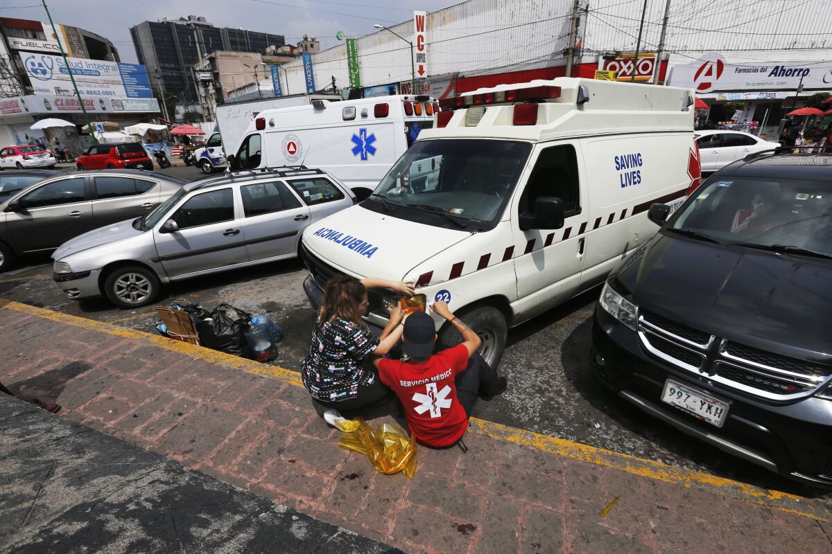 People repair a "pirate" ambulance light outside the General Hospital in Mexico City, Saturday, Sept. 12, 2020. The poorly equipped, often broken-down rattletraps ply Mexico City streets listening to emergency radio dispatch frequencies and race to beat legitimate ambulance services to medical emergencies. (AP Photo/Marco Ugarte)