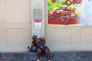 A woman fans herself underneath a crawfish sign outside a grocery store in New Orleans. (Chris Granger/The Advocate via AP)
