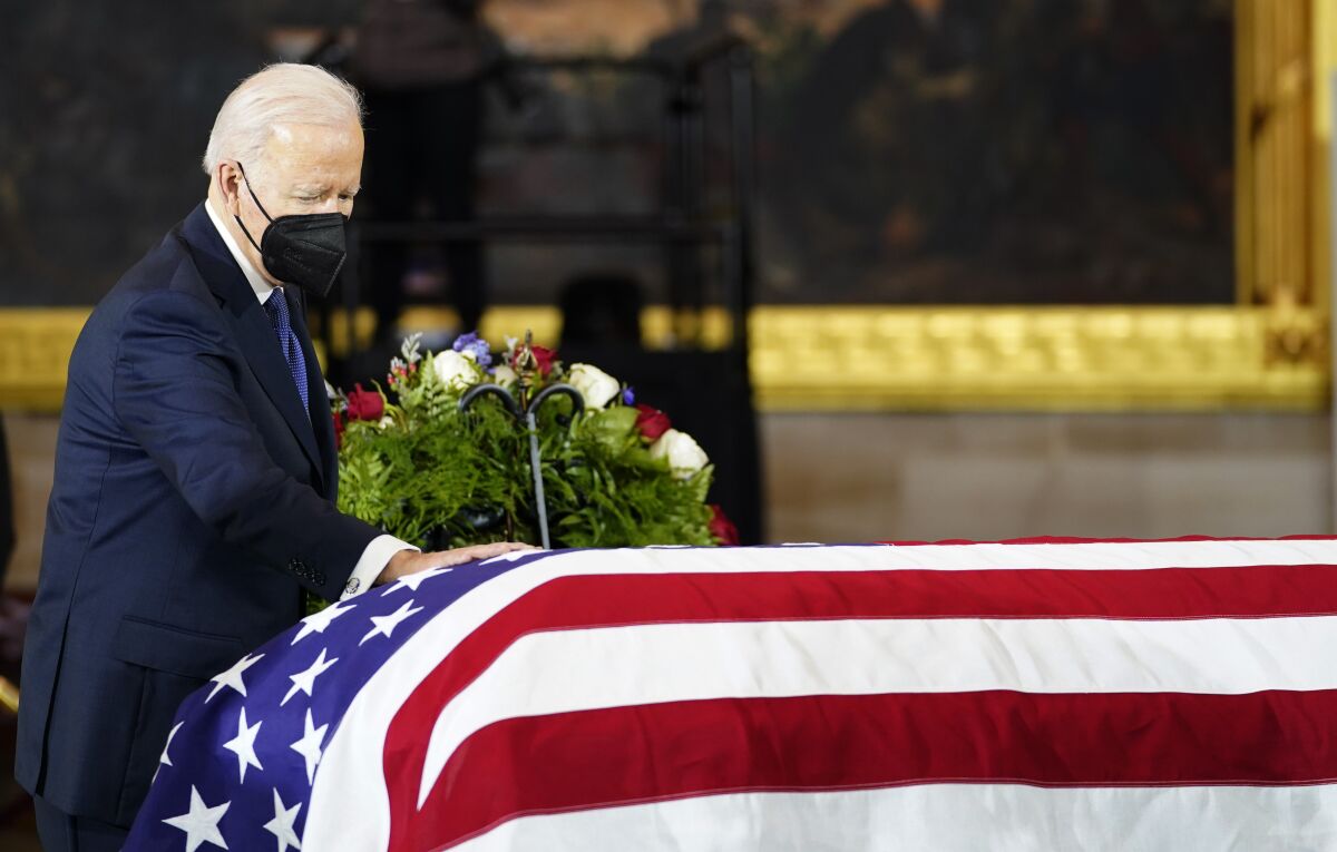 President Joe Biden touches the flag-draped casket of former Senate Majority Leader Harry Reid of Nevada, as he lies in state in the U. S. Capitol Rotunda, Wednesday, Jan. 12, 2022, in Washington. (AP Photo/Mariam Zuhaib)