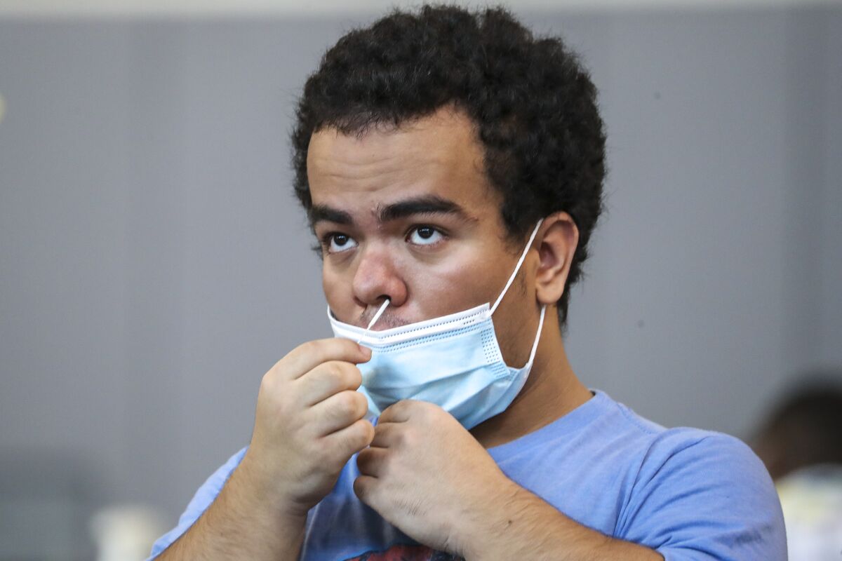 Jorge Morales, 18, swabs his nose to test for the coronavirus